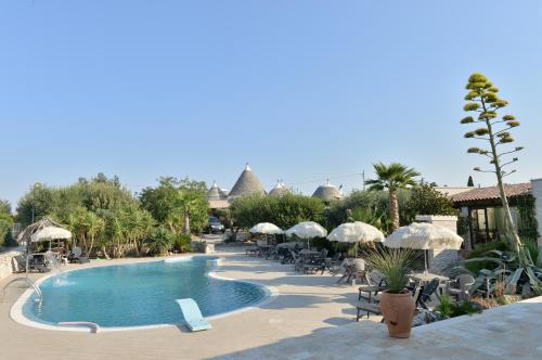 a pool at a resort with chairs and umbrellas at Masseria Pentima Vetrana Resort in Alberobello