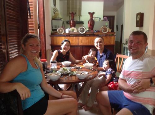 a group of people sitting around a table at The Purple Hue Homestay in Hue