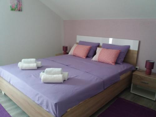 a bedroom with a large bed with purple sheets and pillows at Apartmani Beljkas in Tivat