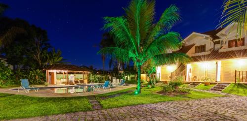 a palm tree in front of a house at night at Recanto da Praia in Paraty