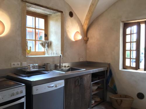 eine Küche mit einer Spüle, einem Herd und Fenstern in der Unterkunft Manoir au sein du village in Saint-Haon-le-Châtel