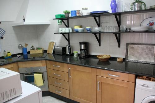 a kitchen with a black counter top and wooden cabinets at Peixe Agulha in Tavira