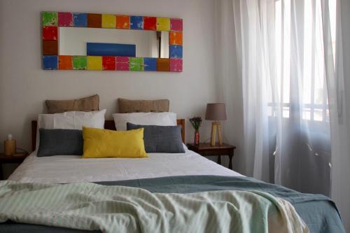 a bedroom with a bed with a colorful painting on the wall at Peixe Agulha in Tavira