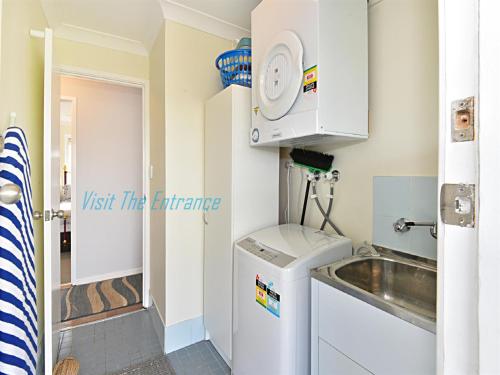 a small kitchen with a sink and a washing machine at The Nautical House in The Entrance