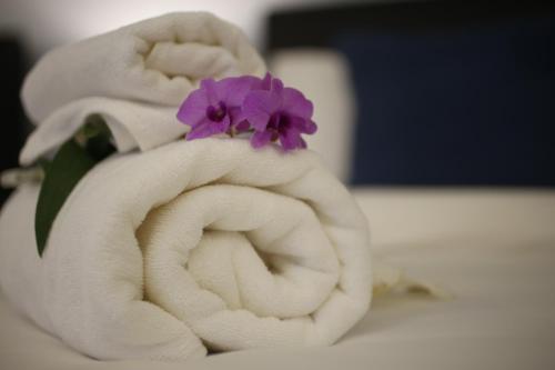 a white towel with a purple flower on it at The White Elephant Home in Chiang Mai