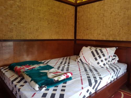 a bed with a green blanket on top of it at Radiya Guesthouse in Sembalun Lawang