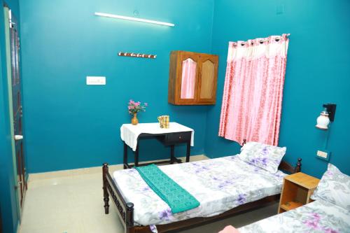 a blue room with a bed and a table with a table at Sajeev Home Stay in Cherai Beach