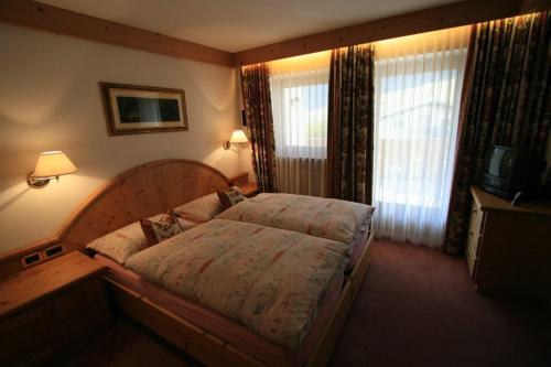 a bedroom with a large bed and a television at B&B Ciasa Weber in Moena