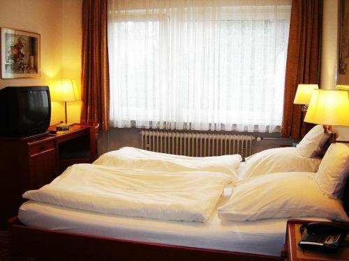 ein großes Bett mit weißer Bettwäsche und einem Fenster in der Unterkunft Hotel - Restaurant Reher Hof in Hagen