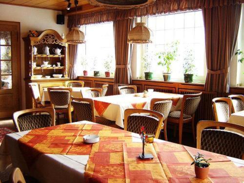uma sala de jantar com mesas, cadeiras e janelas em Hotel - Restaurant Reher Hof em Hagen