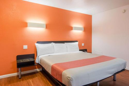 a large bed in a room with an orange wall at Motel 6-Glassboro, NJ - Rowan University in Glassboro