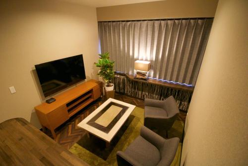 a living room with a flat screen tv and chairs at R&Run Kyoto Serviced Apartment & Suites in Kyoto