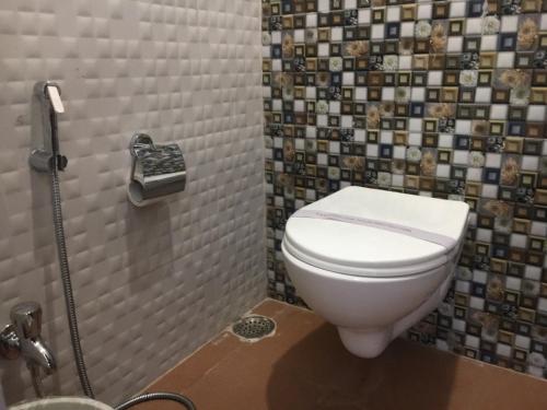 a bathroom with a toilet and a tile wall at Indo Hokke Hotel in Rājgīr