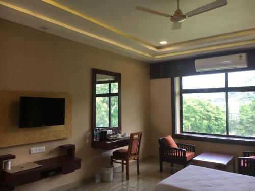 a hotel room with a bedroom with a desk and a tv at Indo Hokke Hotel in Rājgīr