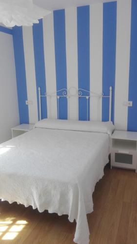 a bedroom with a white bed with blue and white stripes at VuT Dalia 4 in Ávila