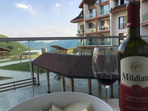 a bottle of wine and a plate of food and a wine glass at New Gudauri 2, Apartment 228 in Gudauri