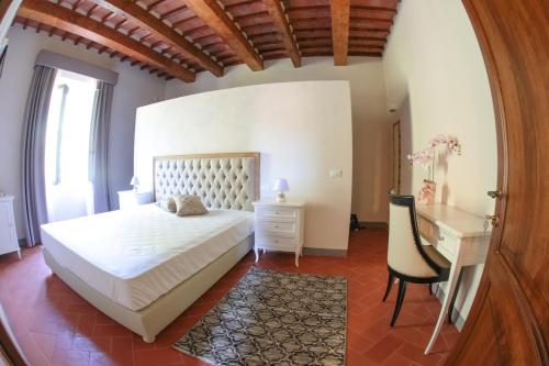 a bedroom with a white bed and a desk at Relais Villa Poschi in Pugnano