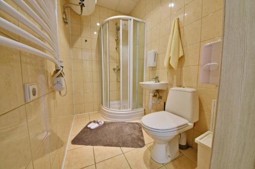 a white toilet sitting next to a shower in a bathroom at Laisves Avenue Hostel "Easy Kaunas" in Kaunas