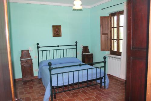 a bedroom with a bed with blue walls and a window at Agriturismo Caliano in Asciano