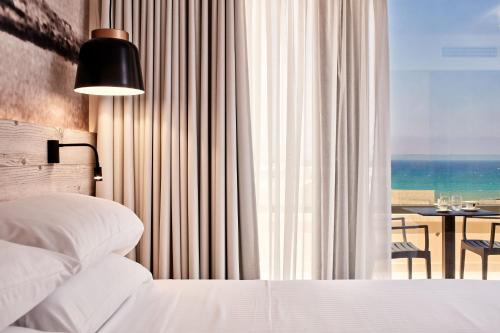 a bedroom with a bed and a view of the ocean at Ibis Styles Heraklion Central in Heraklio Town