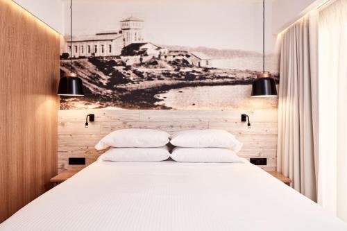 a bedroom with a white bed with a drawing on the wall at Ibis Styles Heraklion Central in Heraklio Town