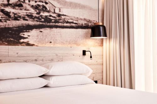 a bedroom with a bed with white pillows and a black lamp at Ibis Styles Heraklion Central in Heraklio Town