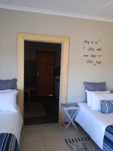 a room with two beds and a door with writing on the wall at Elim Guesthouse in Keimoes