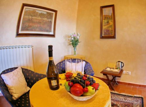 a table with a bowl of fruit and a bottle of wine at Hotel Italia Cortona in Cortona