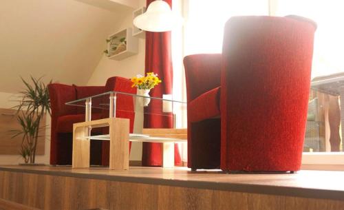 una habitación con sillas rojas y una mesa con flores en Urlaub mit Alpakas, en Sabrodt