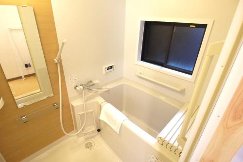 ein Bad mit einer Badewanne und einem Fenster in der Unterkunft Ichimatsu-an in Kyoto