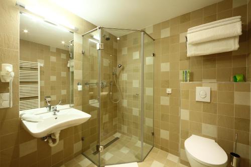 a bathroom with a shower and a sink and a toilet at Hotel Historia Malomkert in Veszprém