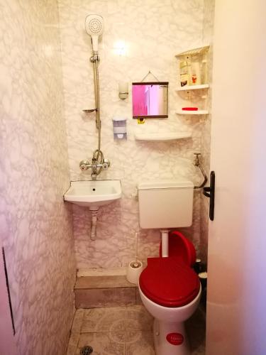 a bathroom with a red toilet and a sink at Sadala Guest House in Nesebar