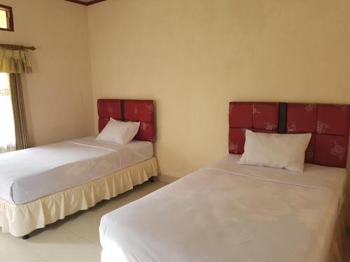 two beds in a room with red headboards at Rinjani Family Homestay in Sembalun Lawang