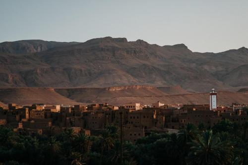 a city in the desert with mountains in the background at Kasbah Petit Nomade in Tinerhir