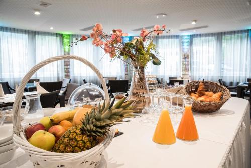 a table with baskets of fruit and flowers on it at Hotel Restaurant La Porte d'Octodure in Martigny-Ville