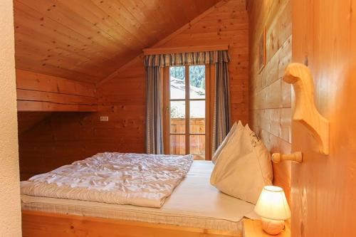 Bett in einem Blockhaus mit Fenster in der Unterkunft Selbstversorgerhütte Nösslau Alm in Dienten am Hochkönig