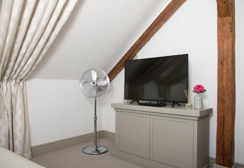 a living room with a tv and a fan at Hotel Kocour in Třebíč