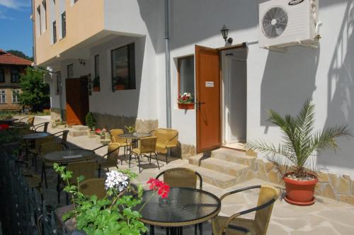 a patio with tables and chairs and a clock on a building at Guest Rooms Biju in Tryavna