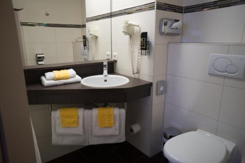 uma casa de banho com um lavatório, um WC e um telefone em Hotel Rödelheimer Hof - Am Wasserturm em Frankfurt am Main