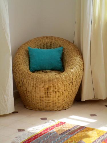 a wicker chair with a blue pillow in a room at La Maison des Ailleurs in Essaouira