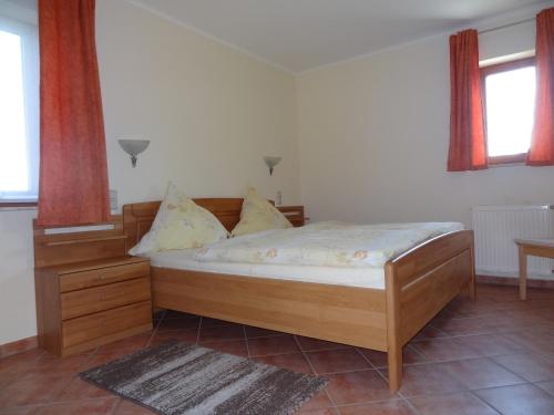 1 Schlafzimmer mit einem Bett mit einem Holzrahmen und 2 Fenstern in der Unterkunft Ferienwohnung Schneider in Mettlach