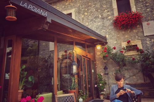 a man sitting outside of a building looking at his cell phone at La Poiana in Barrea