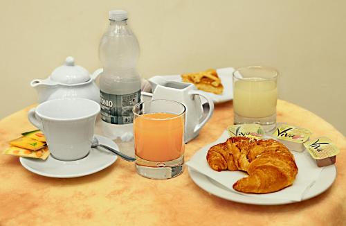 een tafel met een ontbijt van koffie, croissants en drankjes bij Hotel Pavone in Milaan