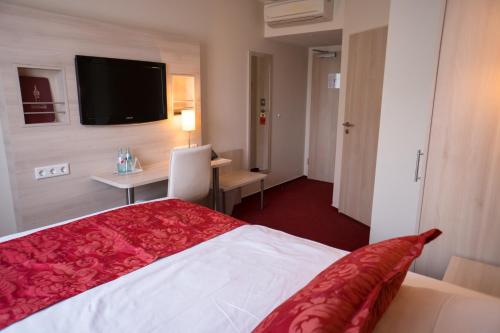 a hotel room with a bed and a desk and a television at Hotel Rödelheimer Hof - Am Wasserturm in Frankfurt/Main