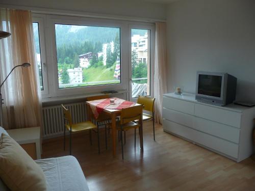 ein Wohnzimmer mit einem Esstisch und einem TV in der Unterkunft Apartment Bergblick in Arosa