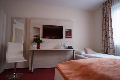 a hotel room with a bed and a tv on a wall at Hotel Rödelheimer Hof - Am Wasserturm in Frankfurt/Main