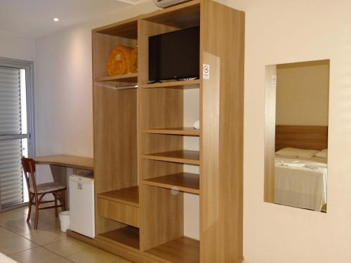 a wooden book shelf with a television in a room at Água Viva Hotel in Olímpia
