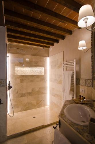 a bathroom with a glass shower with a sink at Dimora Dell'Erbe Rooms in Montepulciano