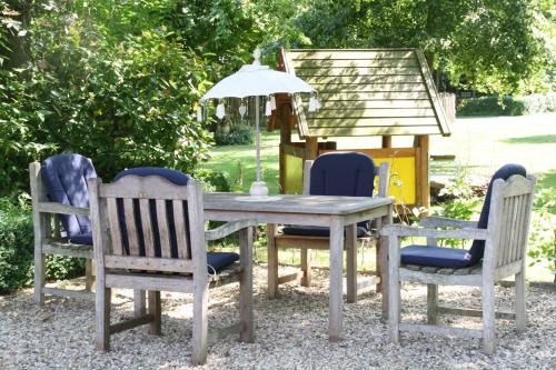 a table and chairs with an umbrella and a bird house at B&B De Sprokkeltuin in Beuningen