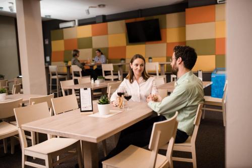 a man and woman sitting at a table in a restaurant at JUFA Hotel Graz Süd - Self Check-in in Graz
